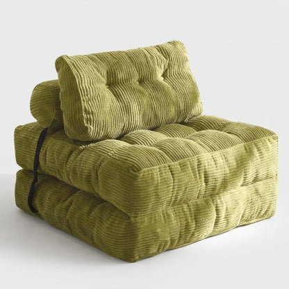 A folded floor cushion or modular chair in olive green corduroy fabric, featuring a tufted backrest and a black strap detail on the side, set against a plain light gray background.