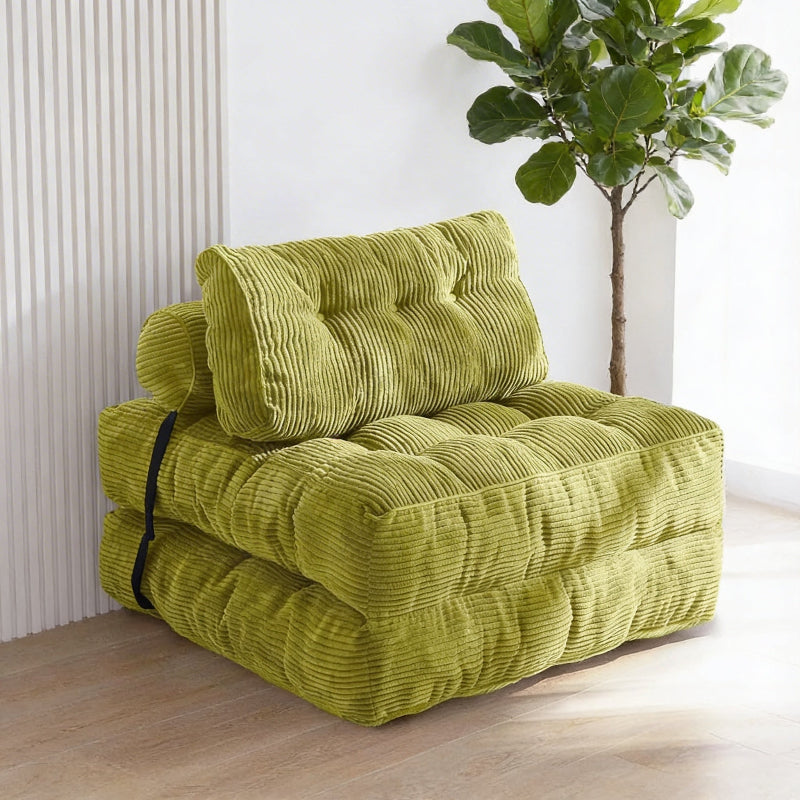 Green corduroy sofa bed in a room with a plant