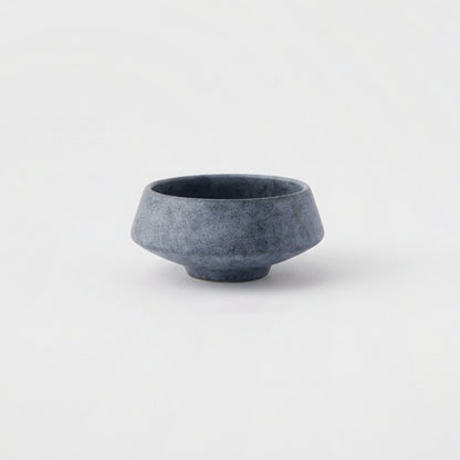 Small matte speckled blue stoneware bowl on a light grey background