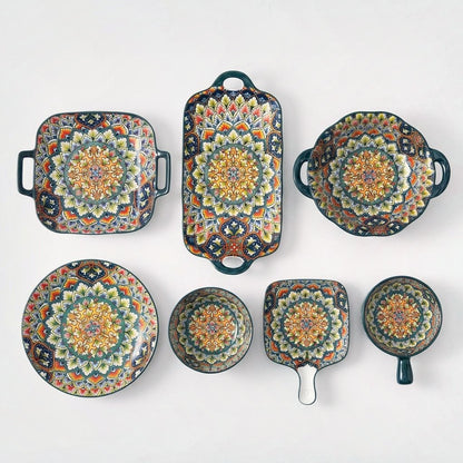 Seven patterned ceramic serving pieces in teal with colorful mandala interiors, including square, rectangular, round, pan and bowl shapes, on a plain light backdrop