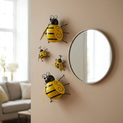 Four metal bumble bee wall decor pieces beside a round mirror indoors