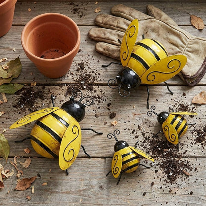Four metal bumble bee decor pieces on a potting bench with garden gloves