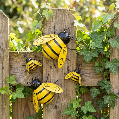 Four metal bumble bee decorations mounted on a wooden fence with ivy