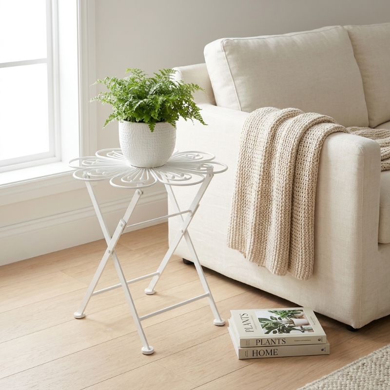Metal flower bistro table on white background with book and plant