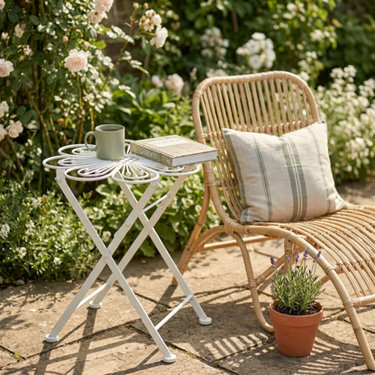 Metal flower bistro table on balcony beside potted plants