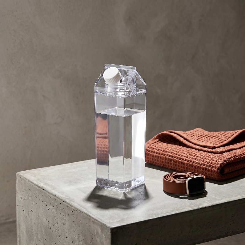 Milk carton style water bottle on table beside folded cloth
