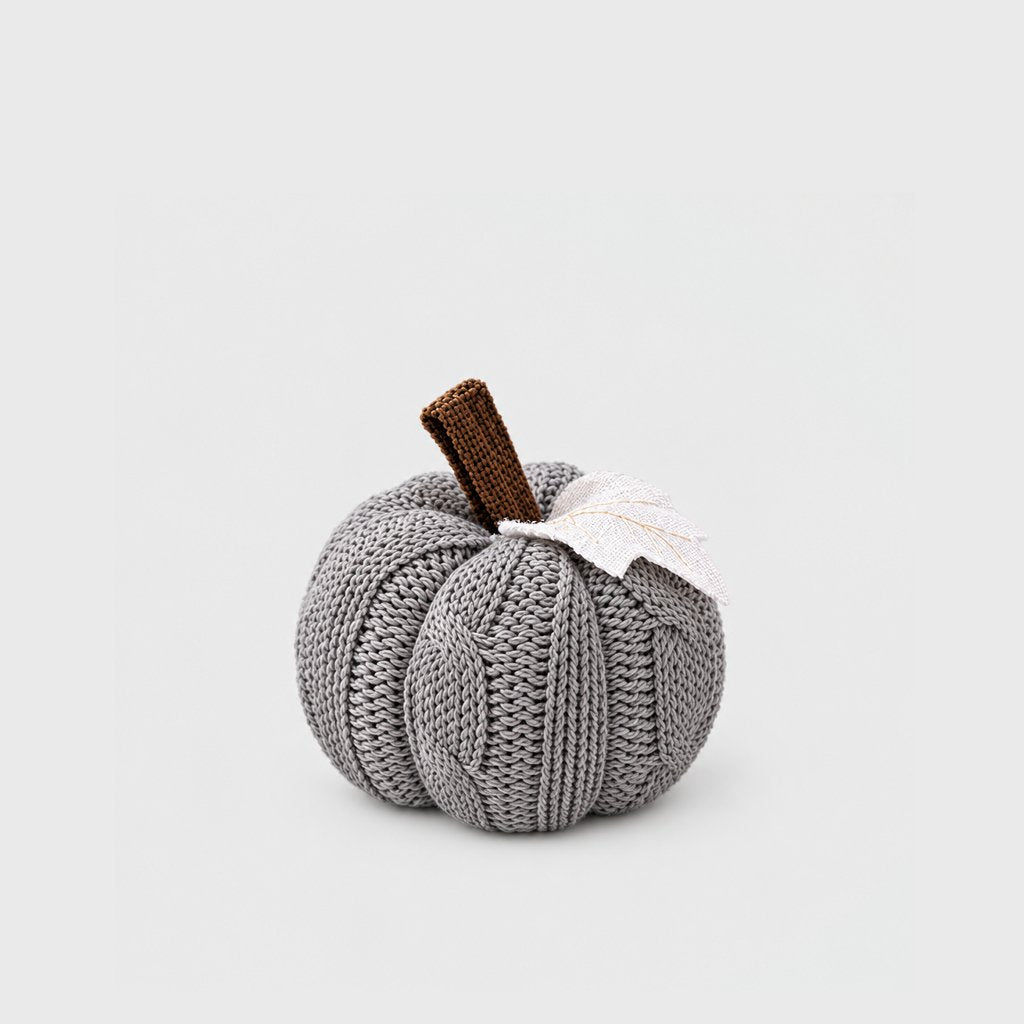 Single grey cable-knit mini pumpkin with a brown stem and white felt leaf on a plain light backdrop