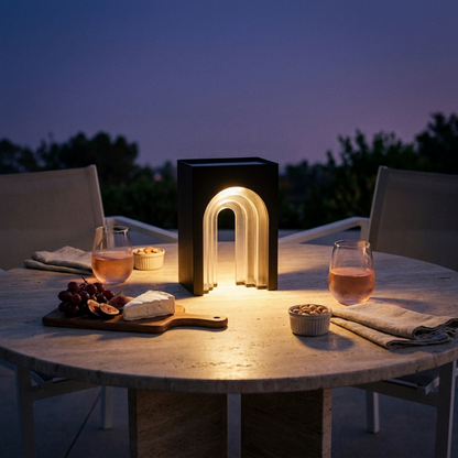 Modern arch solar lantern glowing on outdoor table at dusk