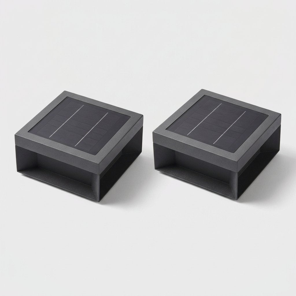 Set of two black solar deck lights with solar panel tops on a light gray studio background