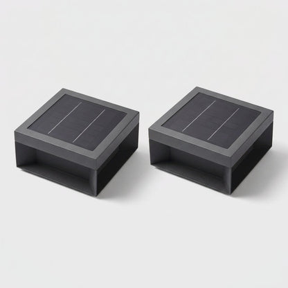 Set of two black solar deck lights with solar panel tops on a light gray studio background