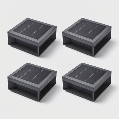 Set of four black solar deck lights arranged in a two by two grid on a light gray studio background