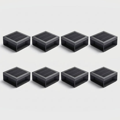 Set of eight black solar deck lights arranged in two rows of four on a light gray studio background