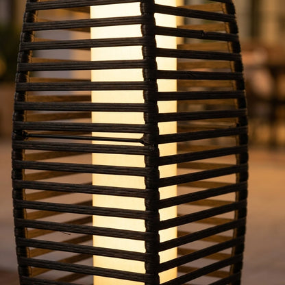 Close-up of the handwoven PE rattan panel on the lantern, showing the herringbone weave and the lit warm-white glow behind it