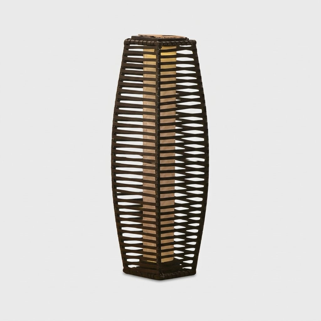 Lit outdoor solar floor lantern with a woven rattan panel and black steel frame on a plain studio background