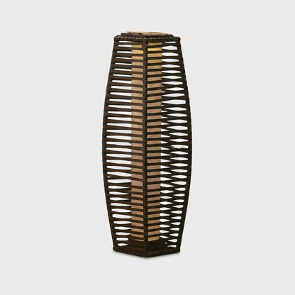 Lit outdoor solar floor lantern with a woven rattan panel and black steel frame on a plain studio background