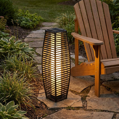 Lit outdoor solar floor lantern on a stone garden path at dusk beside a wooden Adirondack chair and lush greenery