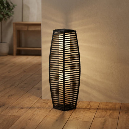 Lit solar floor lantern staged indoors in a room corner beside a console table with a potted plant