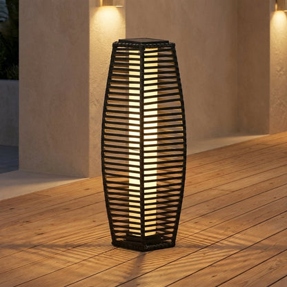 Lit outdoor solar floor lantern in a patio corner at night, framed by stucco walls with wall-mounted sconce lights