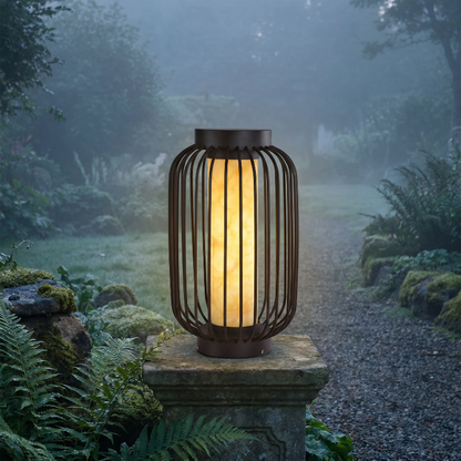 Modern outdoor solar lantern glowing on stone pedestal in misty garden