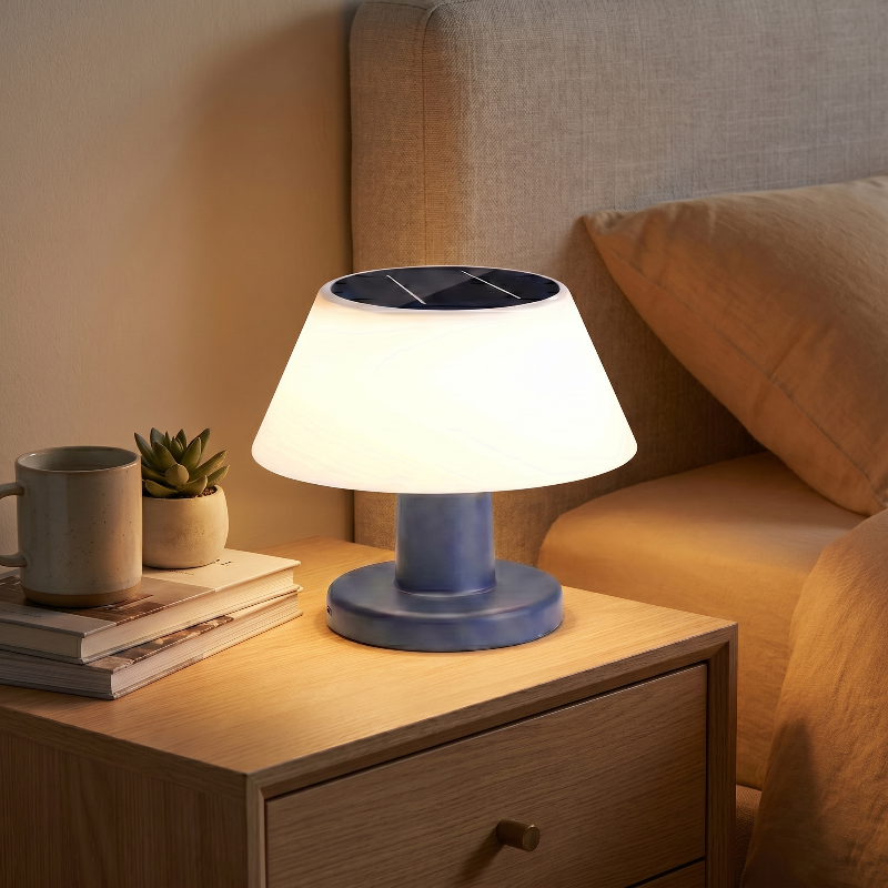 Modern portable solar table lamp on bedside table beside books