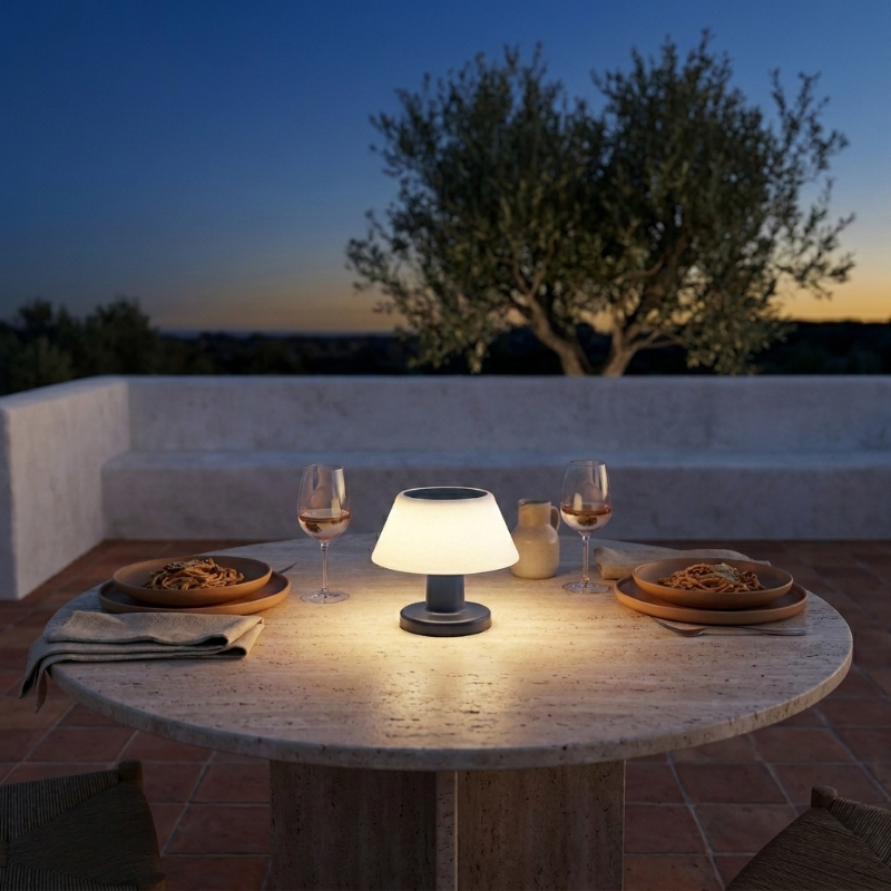 Modern portable solar table lamp on outdoor dining table at dusk