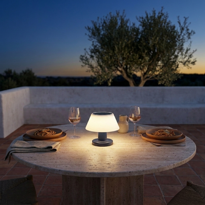 Modern portable solar table lamp on outdoor dining table at dusk