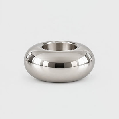 Larger low wide polished silver rounded candleholder with an empty opening on a plain pale gray background