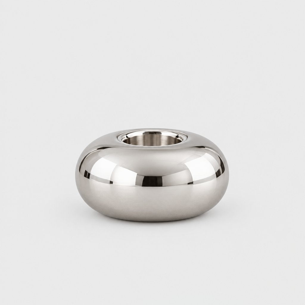 Small low wide polished silver rounded candleholder with an empty opening on a plain pale gray background