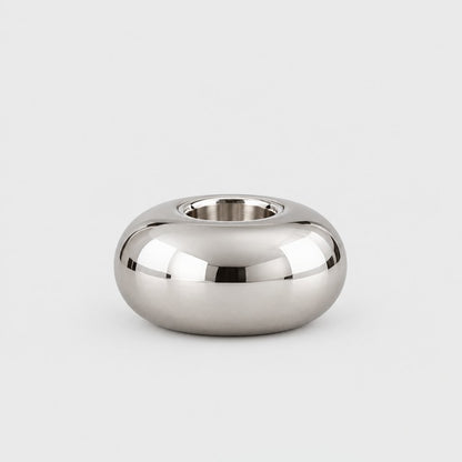 Small low wide polished silver rounded candleholder with an empty opening on a plain pale gray background