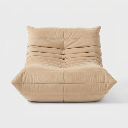 Sand-colored suede tufted lounge chair seen from the front on a light studio background