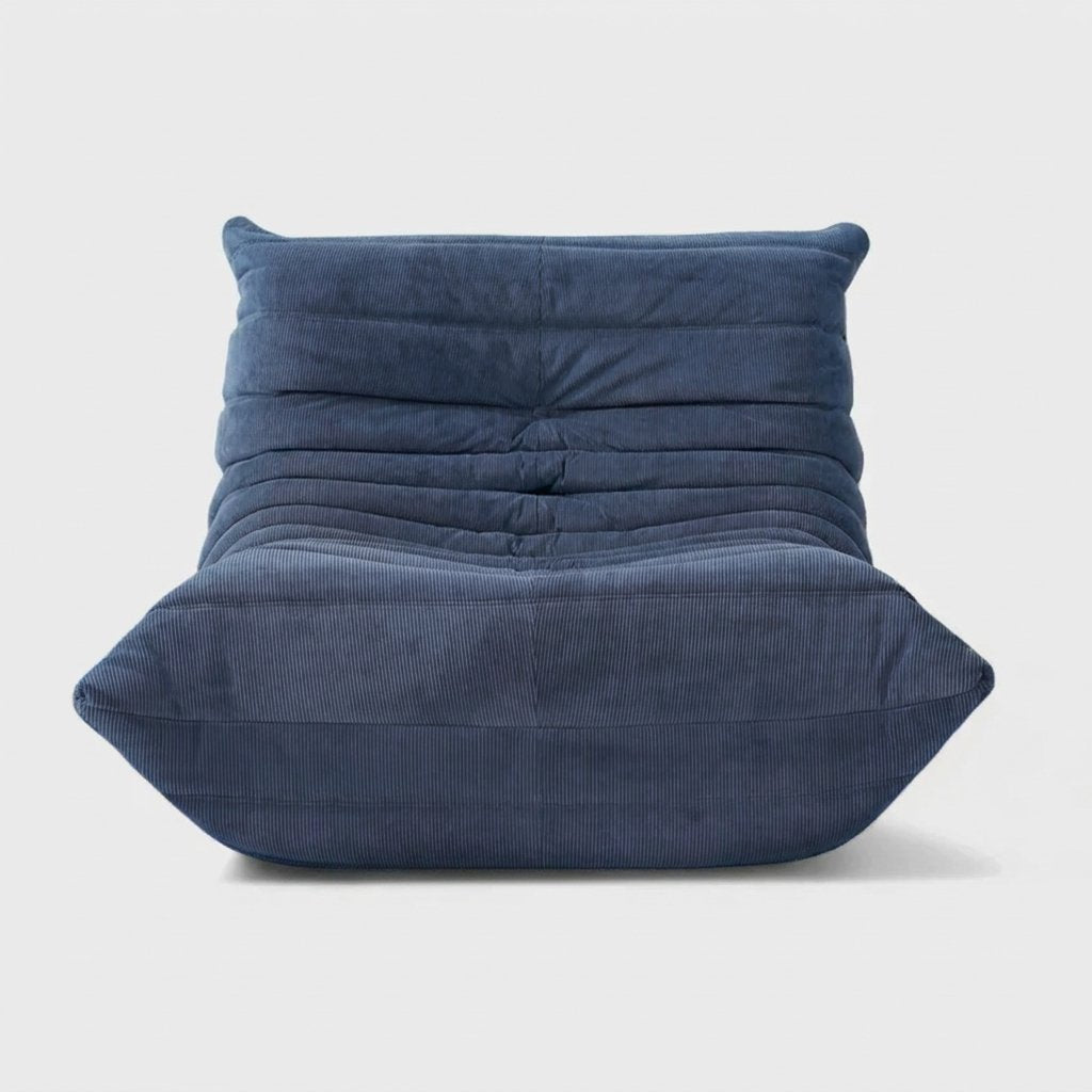 Blue corduroy tufted lounge chair seen from the front on a light studio background