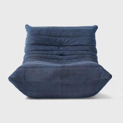 Blue corduroy tufted lounge chair seen from the front on a light studio background