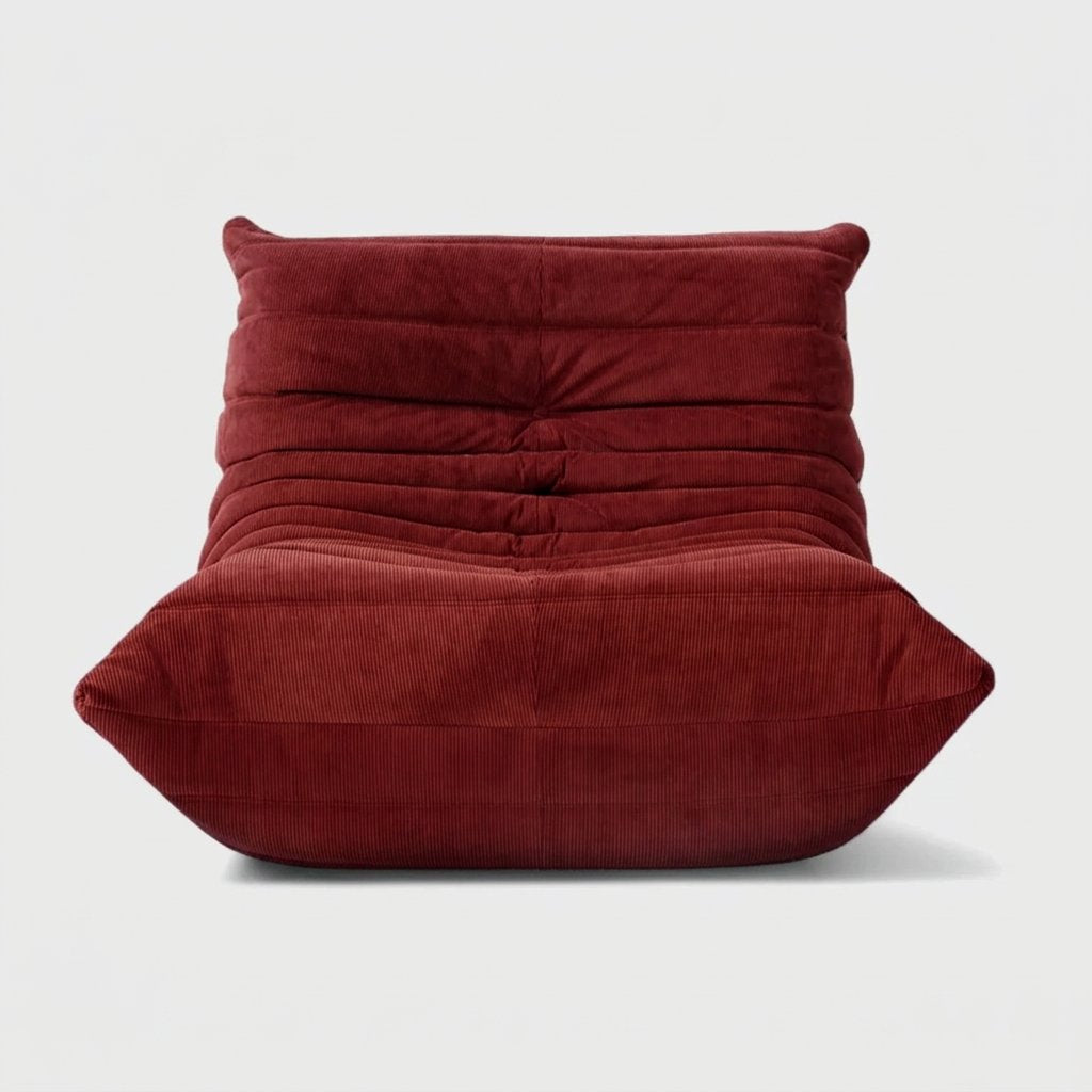 Maroon corduroy tufted lounge chair seen from the front on a light studio background
