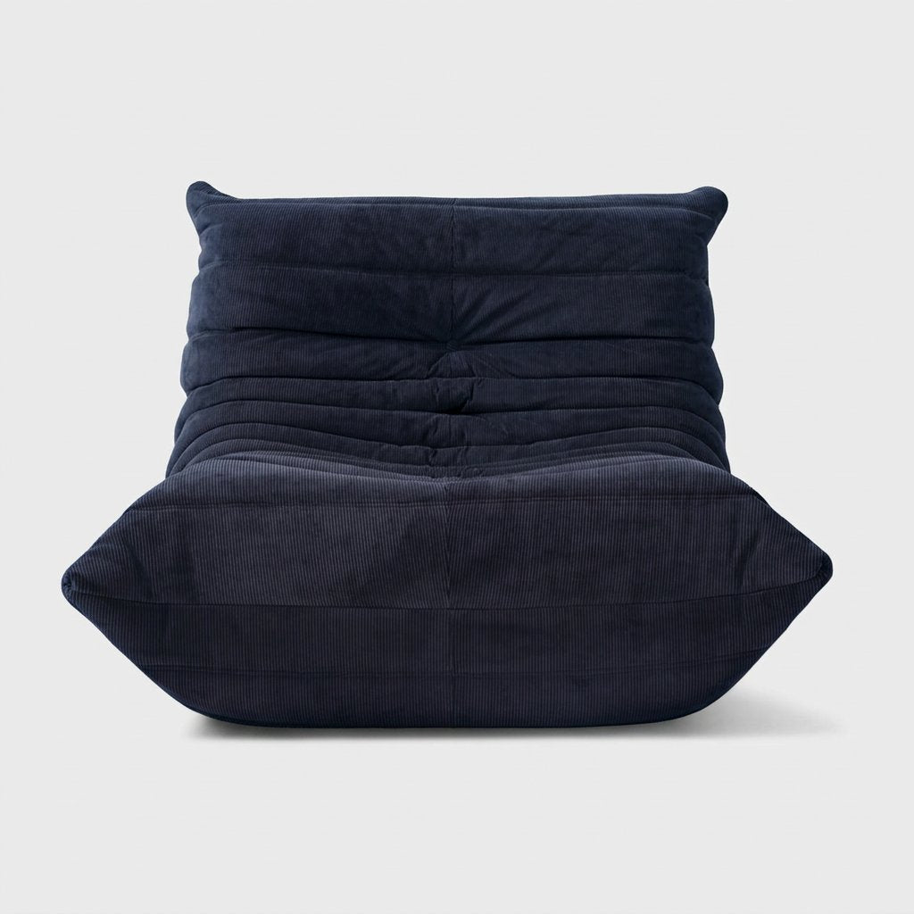 Navy corduroy tufted lounge chair seen from the front on a light studio background