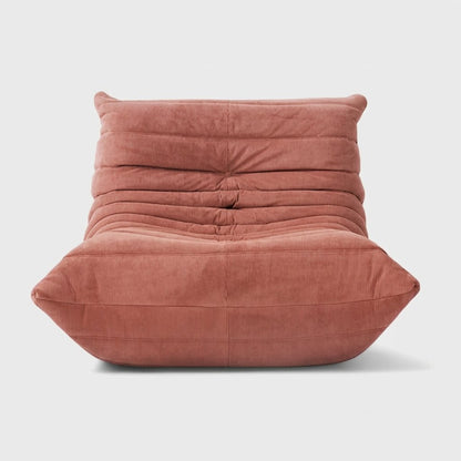 Dusty pink corduroy tufted lounge chair seen from the front on a light studio background