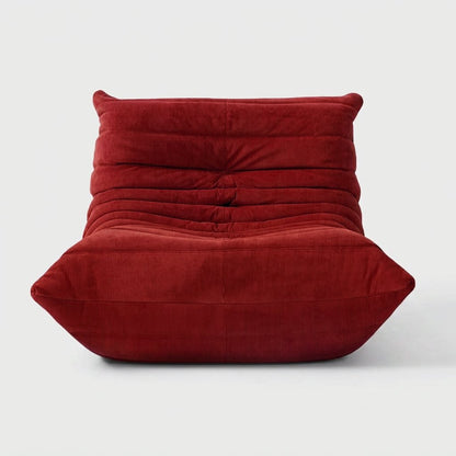 Red corduroy tufted lounge chair seen from the front on a light studio background