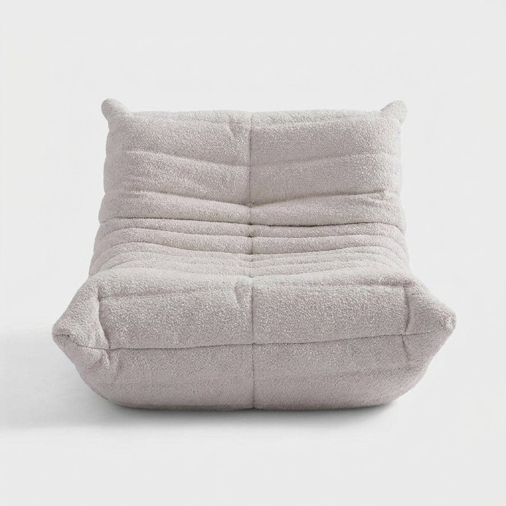 Off-white lamb-wool boucle tufted lounge chair with raised corner ears on a light studio background