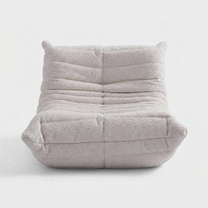 Off-white lamb-wool boucle tufted lounge chair with raised corner ears on a light studio background