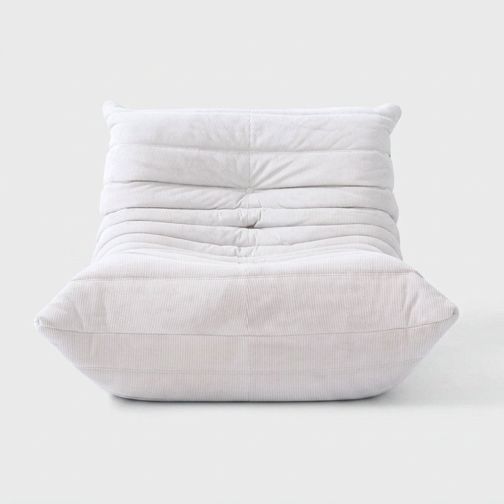 White corduroy tufted lounge chair seen from the front on a light studio background
