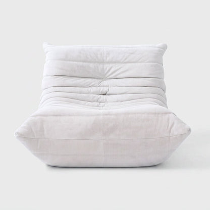 White corduroy tufted lounge chair seen from the front on a light studio background