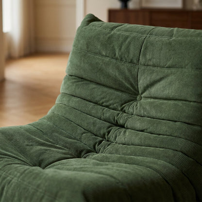 Close-up of the channel tufting and center button on a sage green corduroy lounge chair