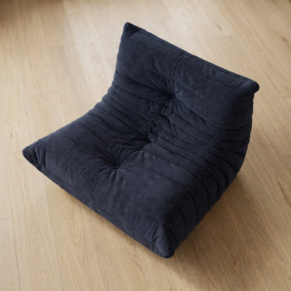 Overhead view of a navy corduroy tufted lounge chair on a light wood plank floor