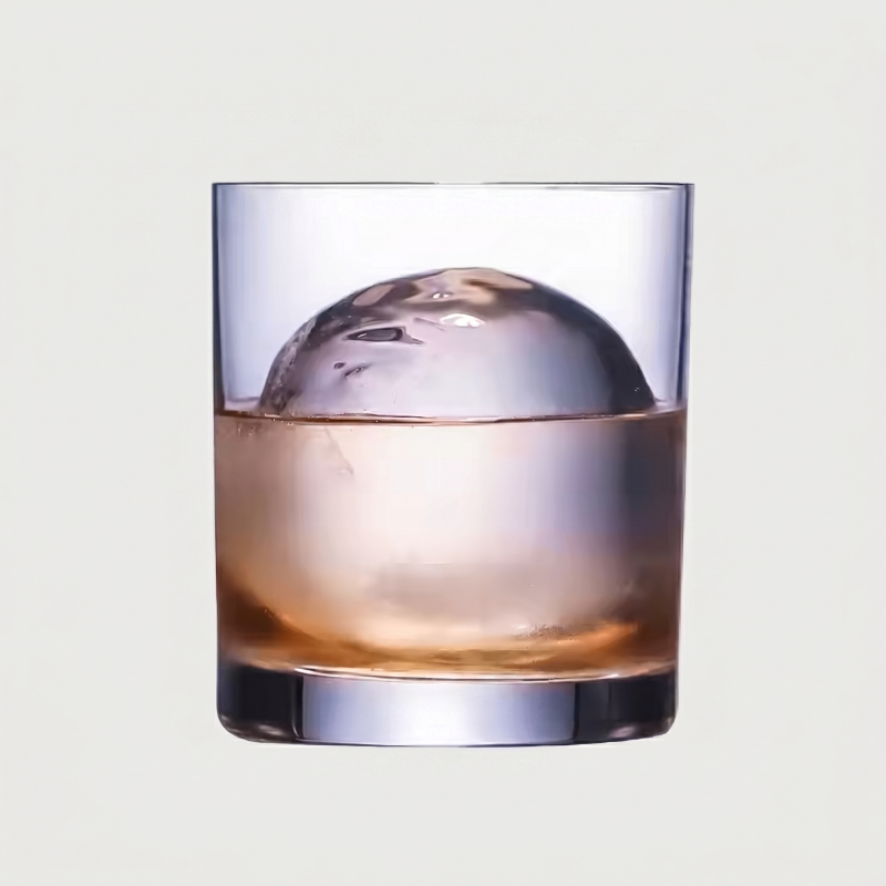 Clear glass with a large ice cube and liquid on a light gray background