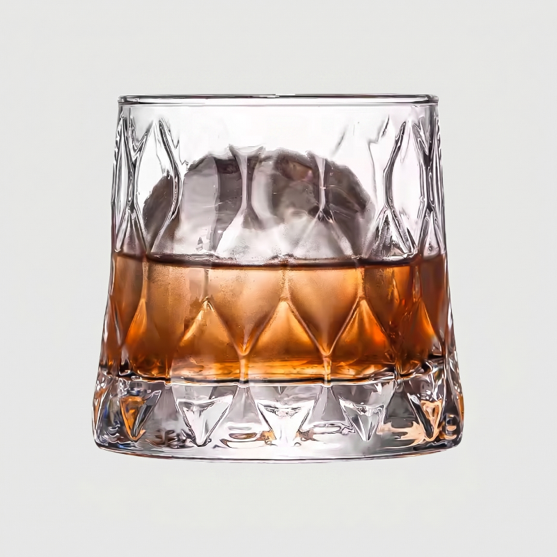 Glass of whiskey with ice cubes on a light gray background