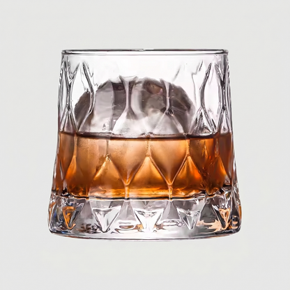 Glass of whiskey with ice cubes on a light gray background