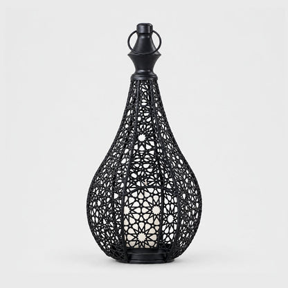 Black cutwork metal lantern with a pointed top and ring handle on a plain light background