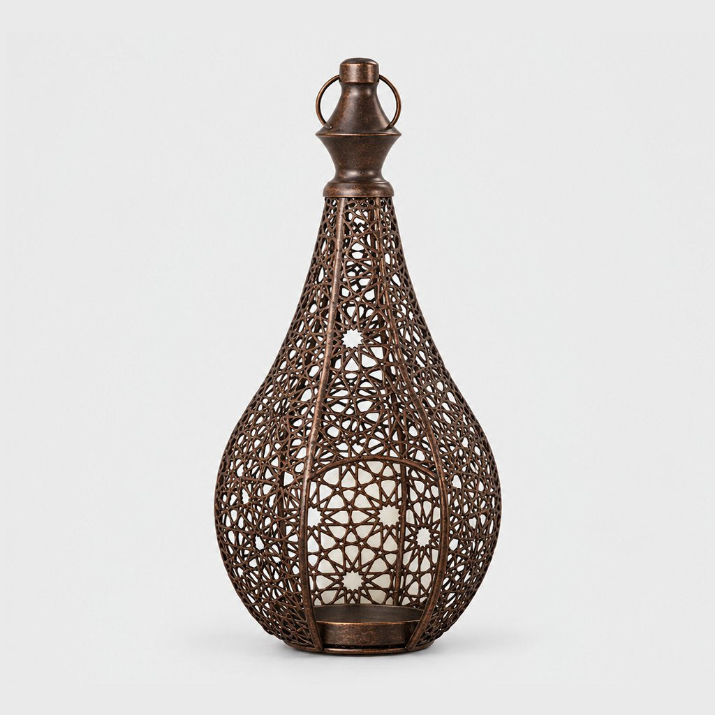 Bronze cutwork metal lantern with a pointed top and ring handle on a plain light background