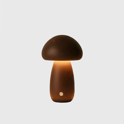 Dark walnut wooden mushroom table lamp with a tall stem, a warm glow and a brass button on a light grey background