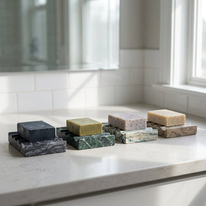 Four Natural Marble Soap Dishes in black, green, white, and natural tones with soap bars displayed on a bathroom counter by a window