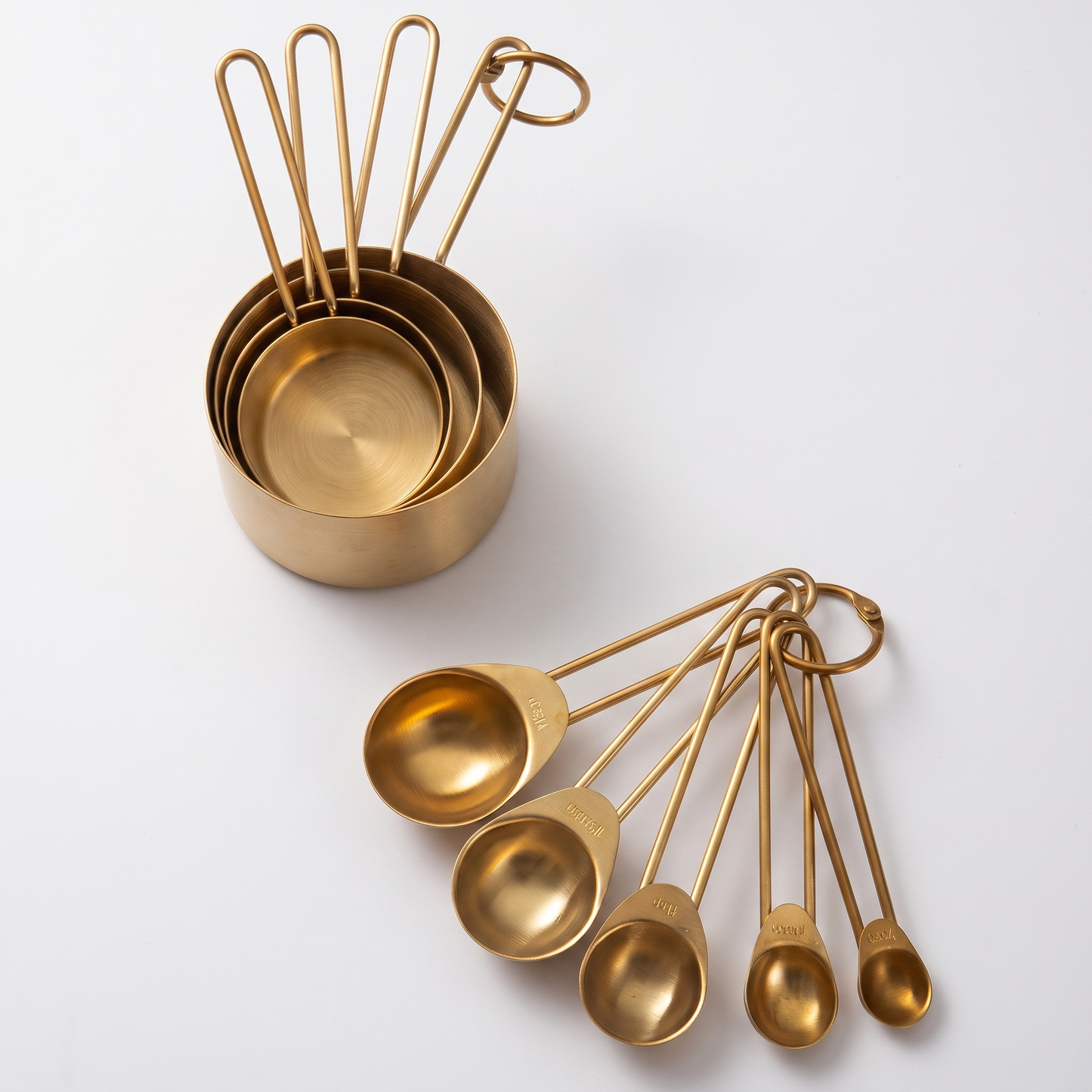 9-Piece Gold Stainless Steel Measuring Set of gold cups and spoons on a clean off-white background